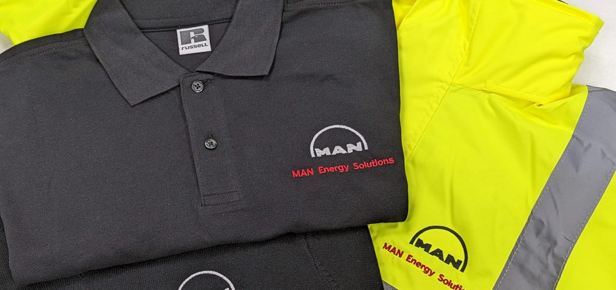 Customised workwear for MAN Energy Solutions, featuring a black polo shirt and a high-visibility yellow jacket.