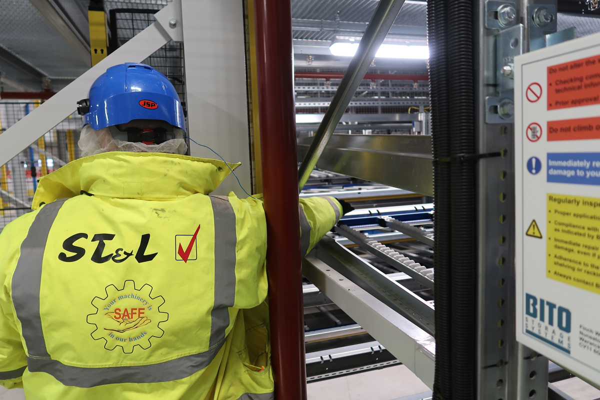 Custom Branded Workwear ST & L branded hi-vis jacket with logo and safety slogan, worn by a worker in an industrial setting with blue hard hat.