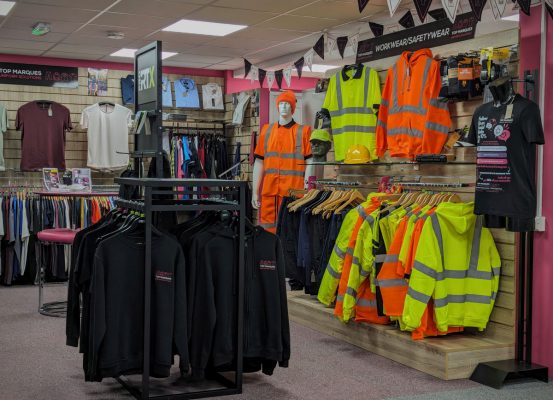 Showroom displaying a variety of high-visibility workwear, professional uniforms, and casual branded apparel.