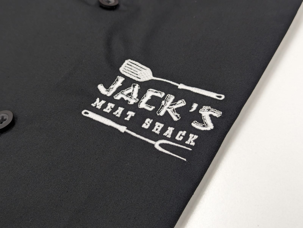 Custom Kitchen wear - Jacks Meat Shack Jack's Meat Shack logo embroidered on black uniform fabric.