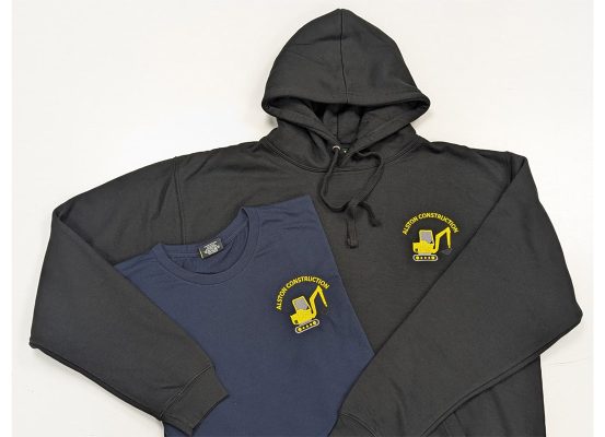 Black hoodie and navy t-shirt for Alston Construction featuring a bright yellow embroidered digger logo on the front.